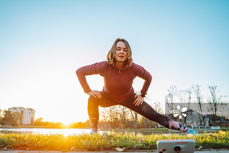 女运动员网红示范正确锻炼方式，运动服女子用手机讲解热身训练图片素材