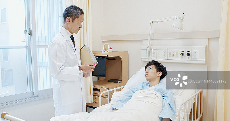 日本医生在病床旁与病人交谈图片素材