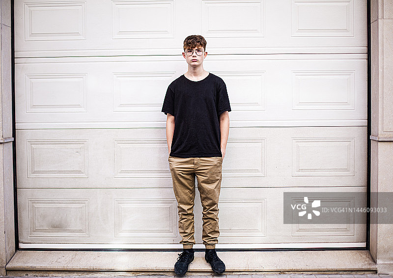 青少年男孩站在车库门前，双手插在口袋里图片素材