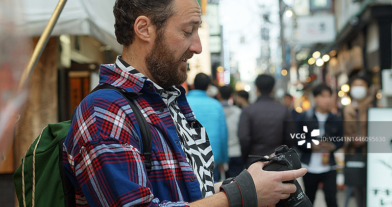 在日本的白人游客正在看他的相机图片素材
