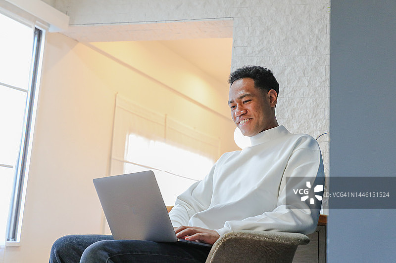 年轻的黑人男子在家使用笔记本电脑图片素材