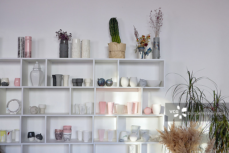 靠白色墙壁摆放各种罐子的书架图片素材