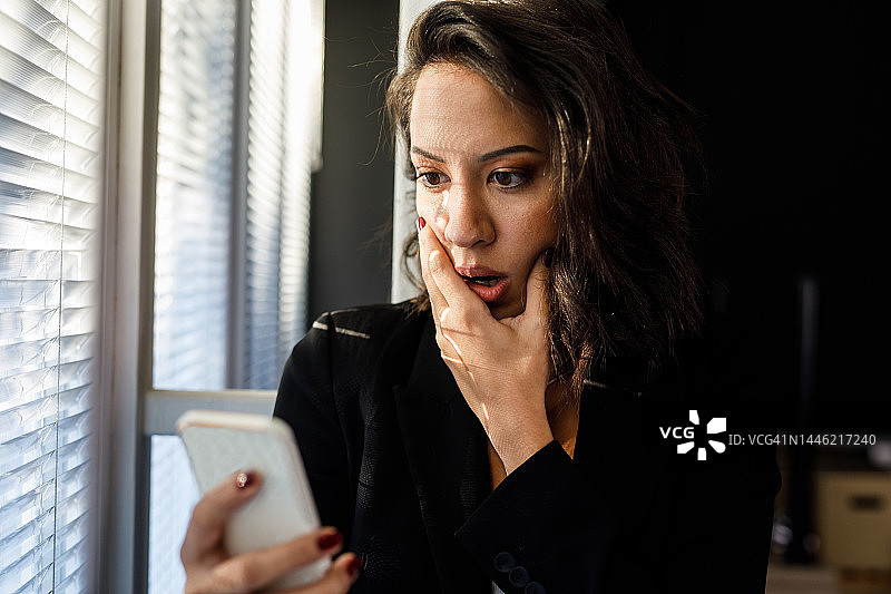 年轻女人在阅读短信后感到震惊图片素材