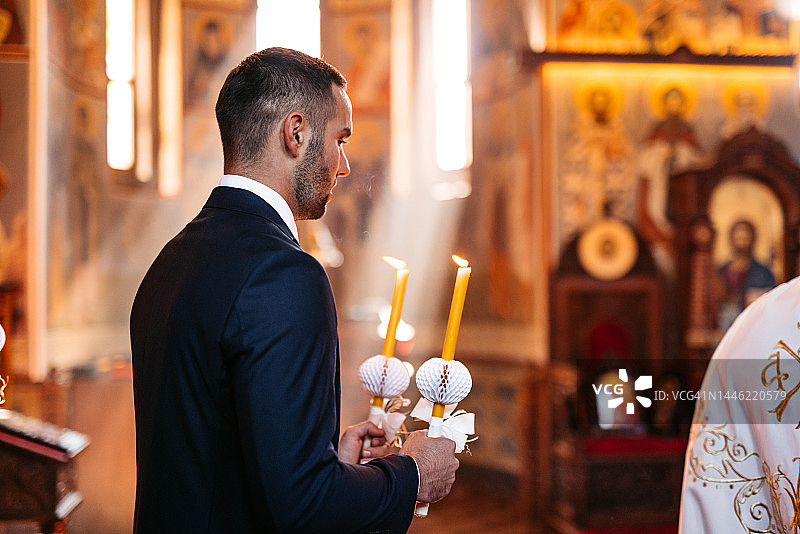 在教堂婚礼上拿着蜡烛的新郎图片素材