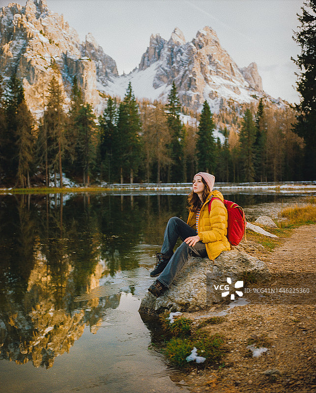 在秋季多洛米蒂湖背景下，坐在湖边的女人图片素材