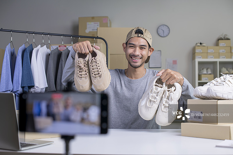 年轻的亚洲电商男店主查看产品图片素材