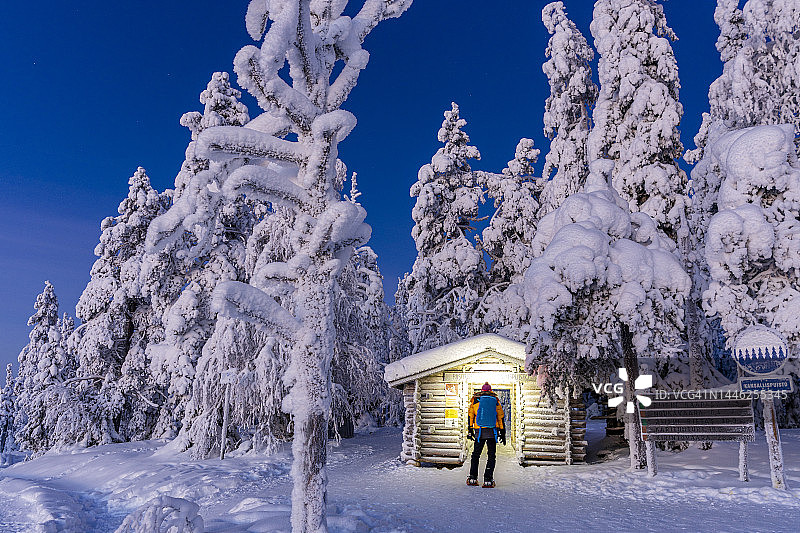 男子穿着雪鞋欣赏雪山小屋图片素材