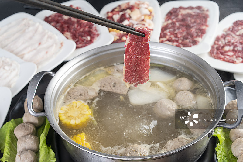 筷子从火锅里夹起牛肉片图片素材