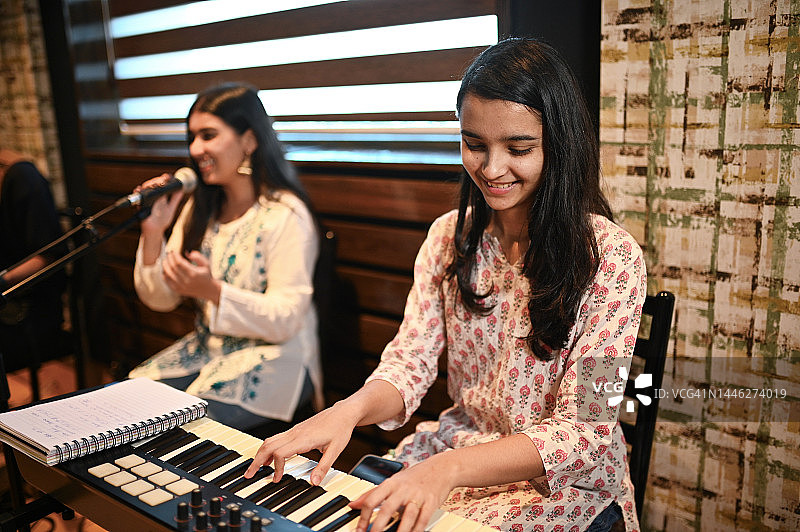 年轻女子演唱印度古典歌曲，另一女子弹奏键盘图片素材