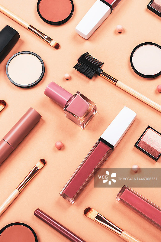 米色、棕色背景上的各种化妆品配件，包含护肤彩妆产品，如眼影、腮红、粉饼、指甲油、刷子和口红，竖版图片素材