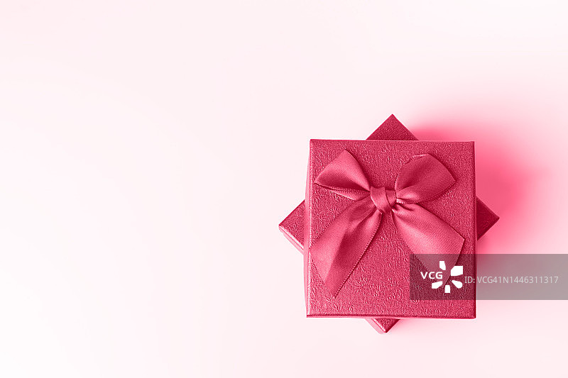 粉色背景上打开的棕色礼品盒正面图。简约的圣诞节和新年概念。节日概念。2023年年度色彩展示。年度色彩。Viva Magenta。图片素材