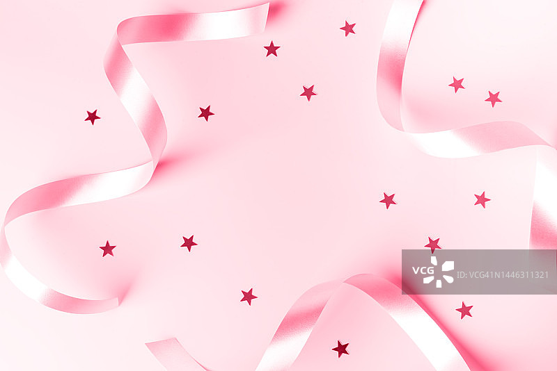 2023年度代表色演示：Viva Magenta，银色卷曲丝带和粉色背景上的五彩纸屑星星，派对、生日、周年纪念、圣诞节、新年庆祝概念设计图片素材