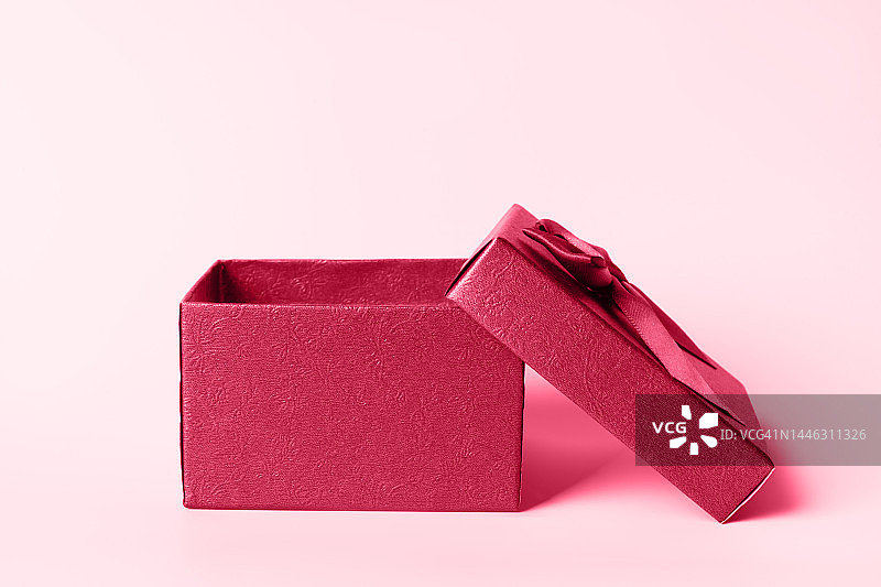 粉色背景上打开的棕色礼品盒正面图。简约的圣诞节和新年概念。节日概念。2023年年度色彩展示。年度色彩。Viva Magenta。图片素材