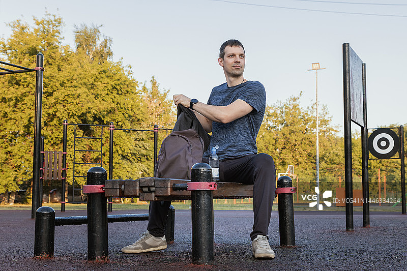 积极的男人在早晨运动训练前坐在长凳上，准备运动图片素材