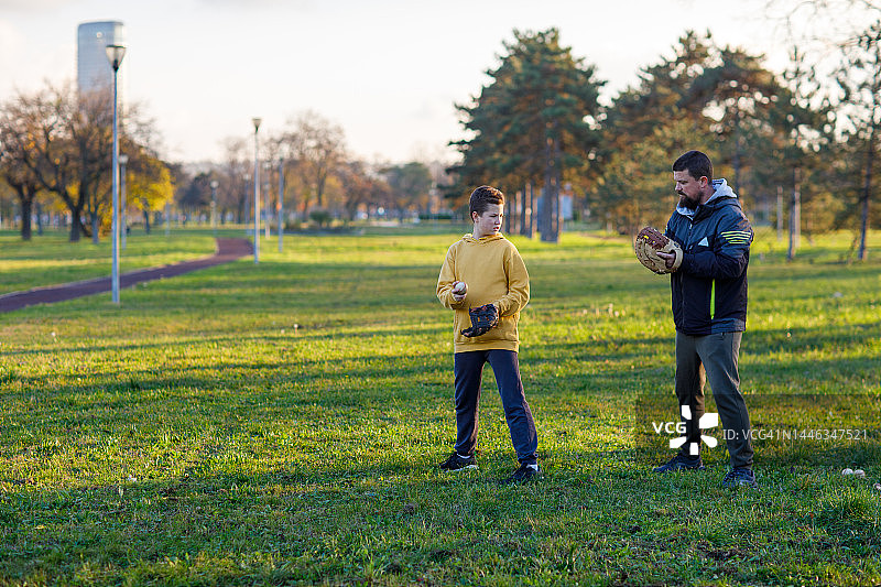 12岁男孩向父亲学习投球规则图片素材