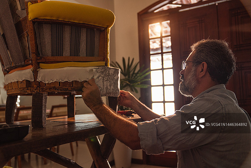 一位正在家中重新装饰扶手椅的老年男人图片素材