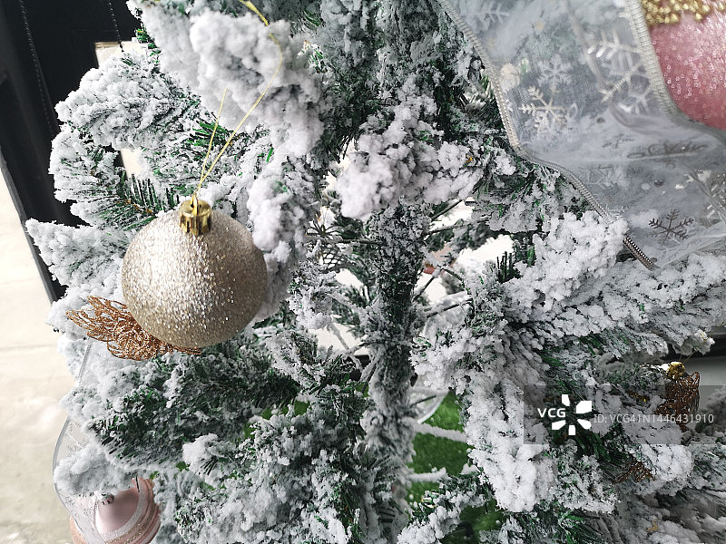 圣诞节绿色松树人造雪覆盖悬挂金球背景图片素材