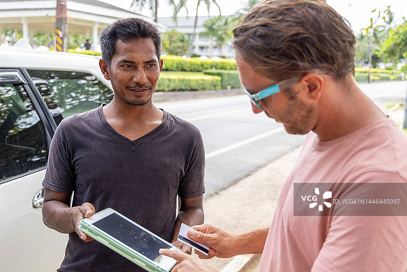 游客使用数字应用程序上的信用卡支付当地出租车费用图片素材