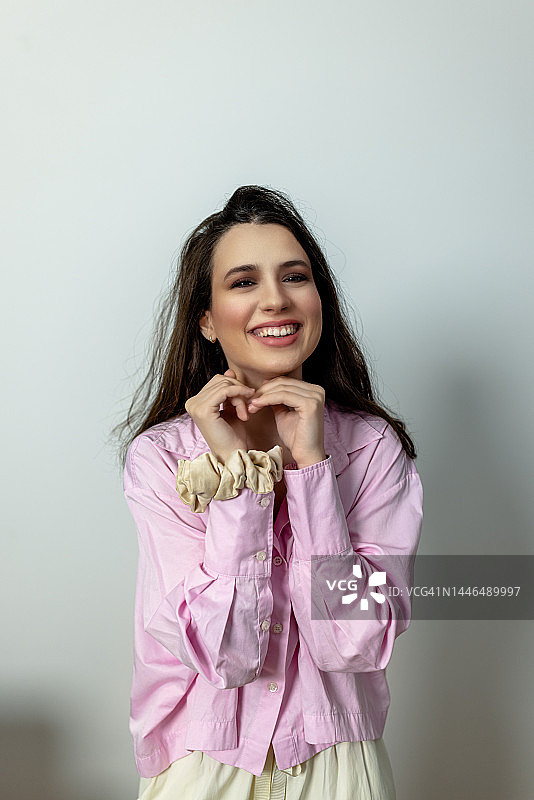 一位时髦的年轻女性在工作室对着镜头微笑的肖像图片素材