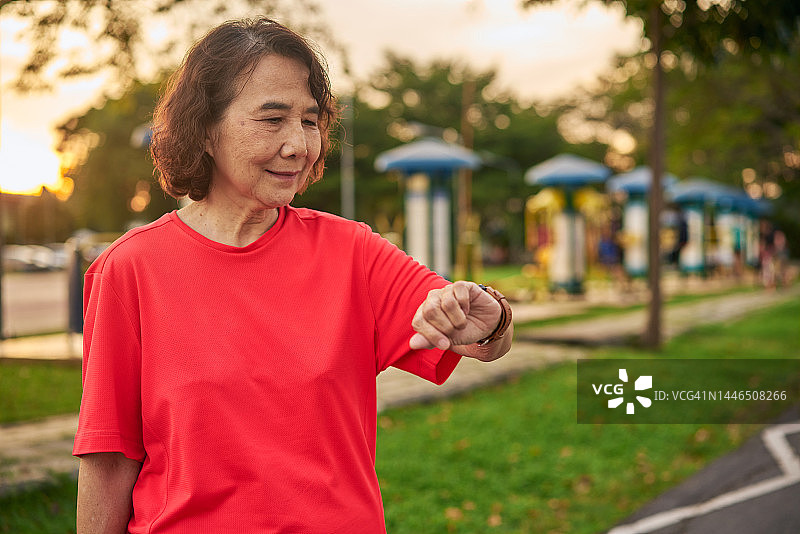 老年妇女在公园慢跑后，查看智能手表上的心率和方向图片素材