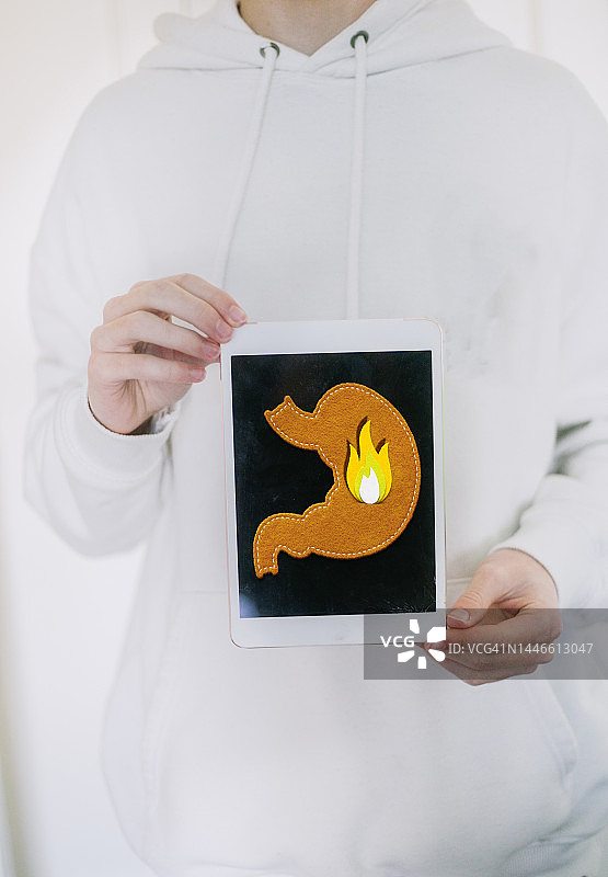 男人手持平板电脑，屏幕显示胃部疼痛图片素材