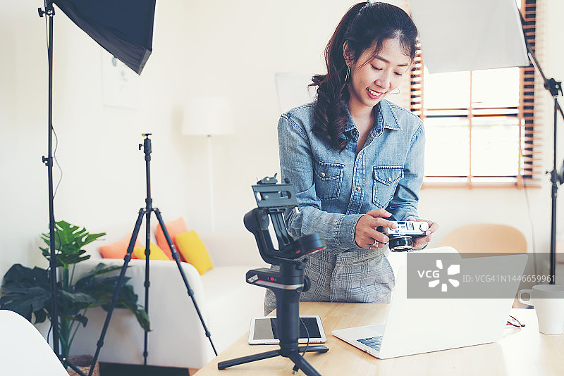 居家办公室内，年轻女摄影师手持单反相机图片素材