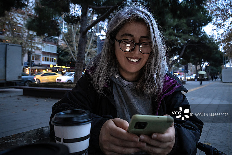 在咖啡馆室内人行道上看手机的女人图片素材