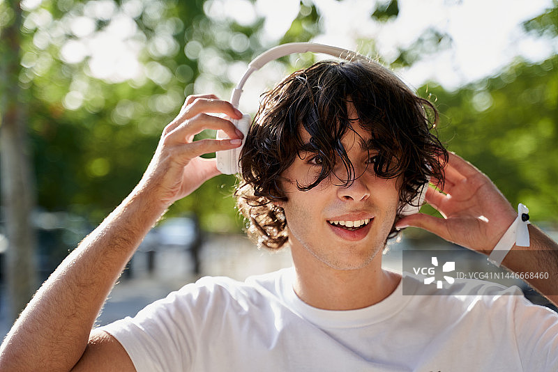 无忧无虑的年轻白人少女在街头戴耳机听音乐图片素材