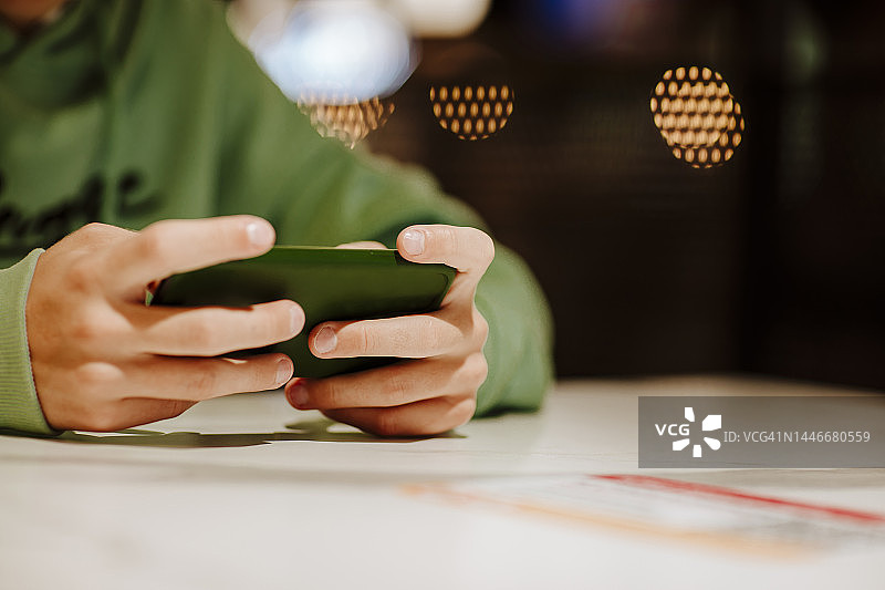 男孩在美食广场的餐桌上使用智能手机图片素材