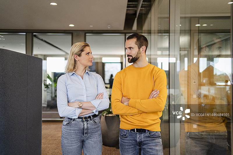 办公室里交叉双臂、互相注视的商业伙伴图片素材