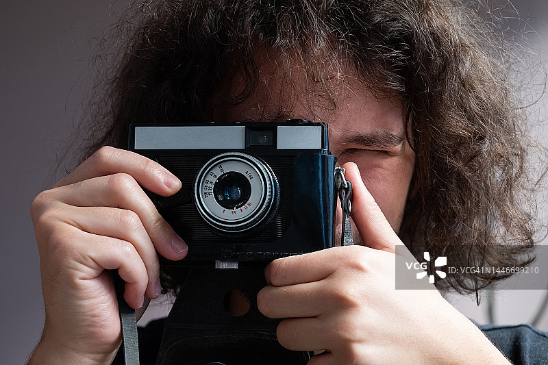 男人用复古相机拍照，创意自由职业者或学生用相机拍照图片素材