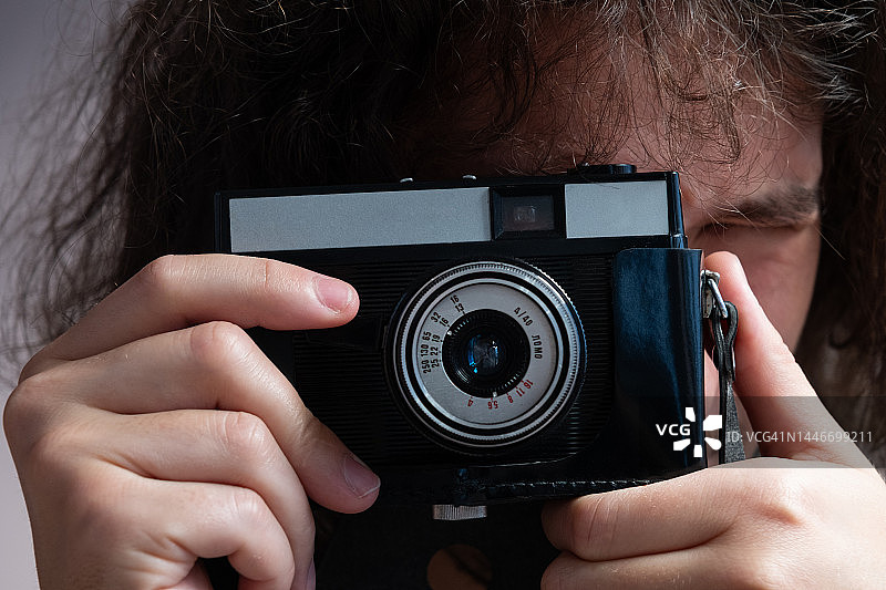 男人用复古相机拍照，创意自由职业者或学生用相机拍照图片素材