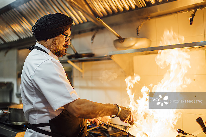 在餐厅厨房烹饪食物的印度厨师图片素材