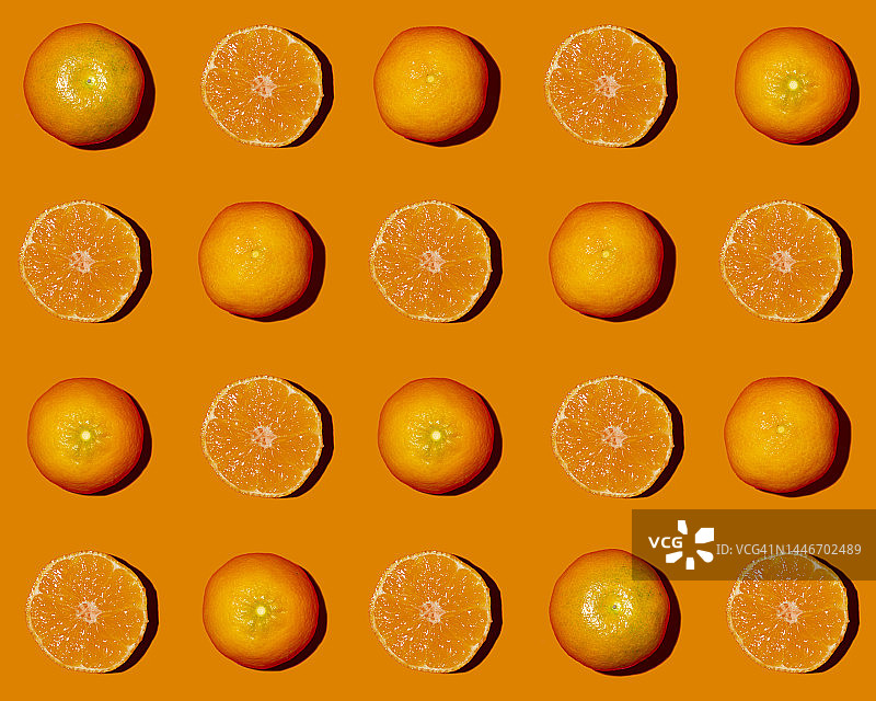 对半切开的橘子平铺在橙色背景上的图案图片素材