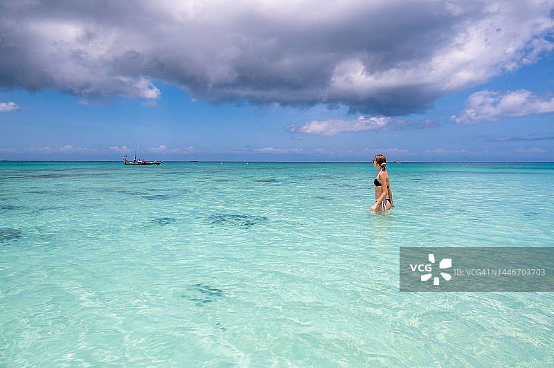 女孩在坦桑尼亚肯德瓦海滩看着渔船图片素材