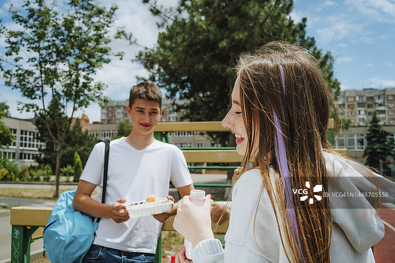 快乐的女孩拿着瓶子，朋友在背景中吃午饭图片素材