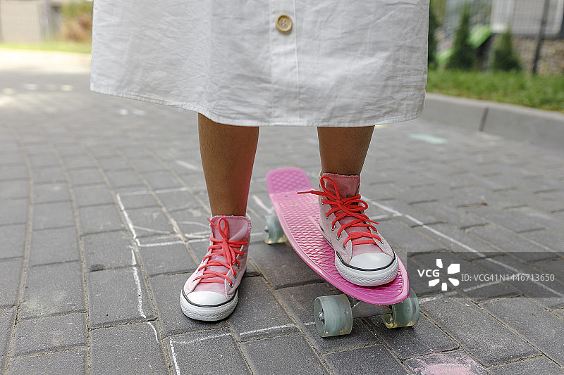 站在人行道上拿着粉色滑板的女孩图片素材