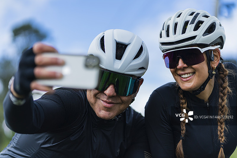 情侣骑着白色自行车在卡希卡-昆迪纳马卡路上行驶，戴着安全头盔和骑行眼镜图片素材