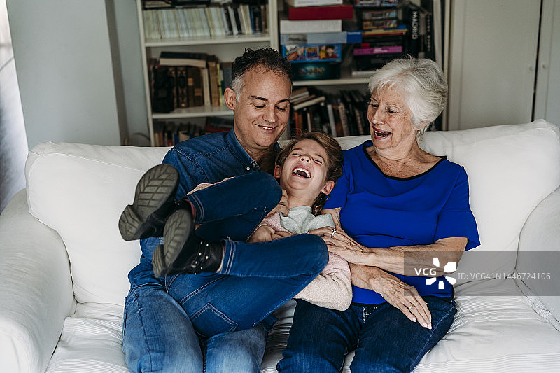 开心的女孩和父亲、祖母在家中沙发上享受时光图片素材