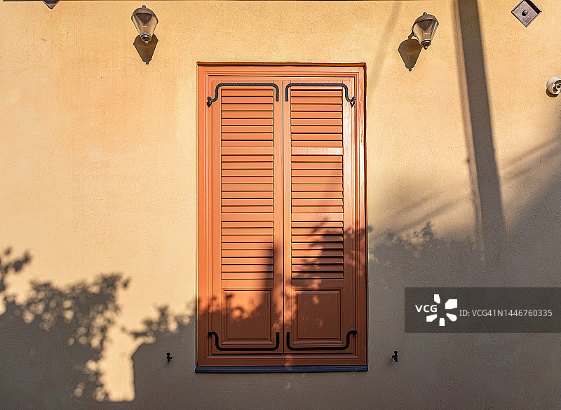 黄色墙壁上的橙色百叶窗图片素材