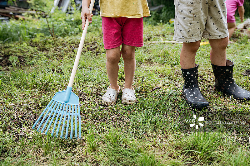 儿童腿部穿靴子拿耙子特写图片素材