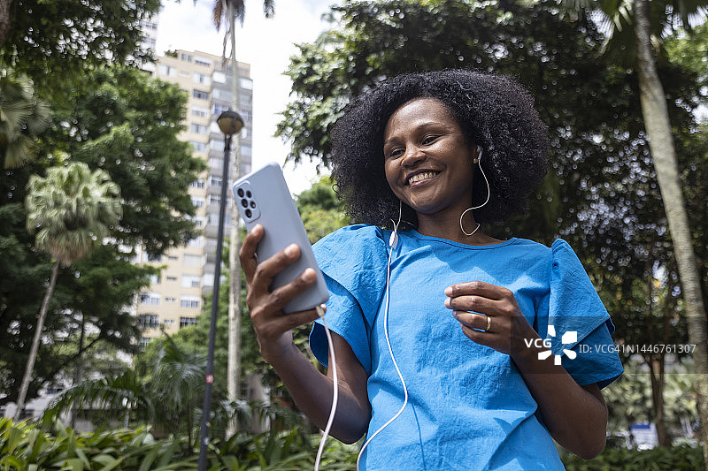 戴着耳机使用手机的黑人女性图片素材
