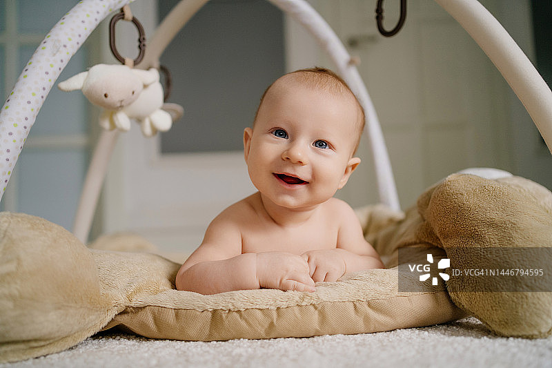 笑容满面的新生婴儿躺在婴儿床里看着镜头图片素材