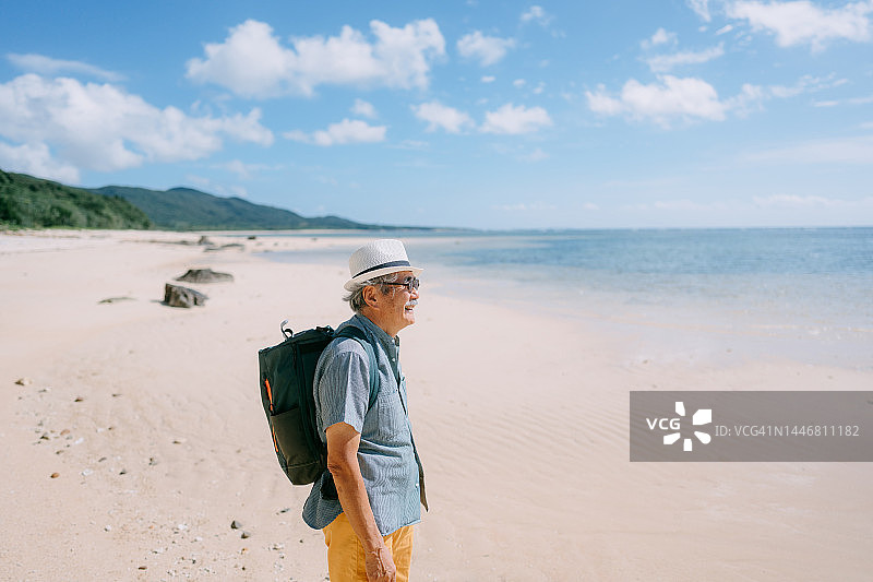 年长的男人站在海滩上看着大海图片素材