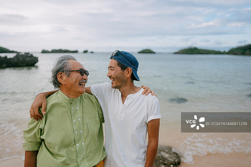 年长的父亲和成年的儿子在黄昏时分的海滩上玩耍图片素材