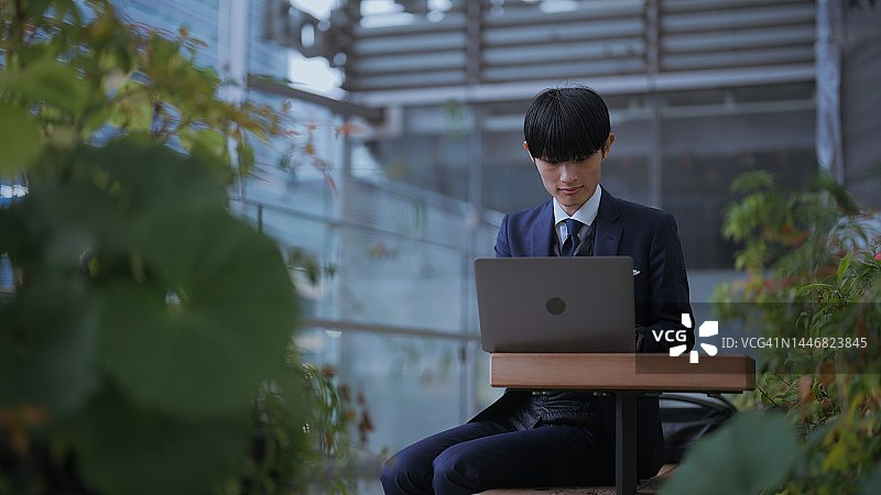 商人在城市避雨并使用笔记本电脑图片素材