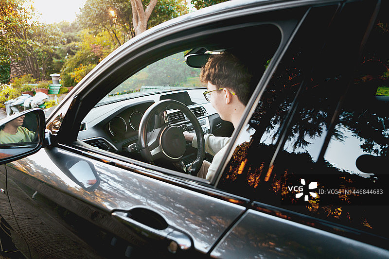 男孩坐在车里展示新驾照图片素材