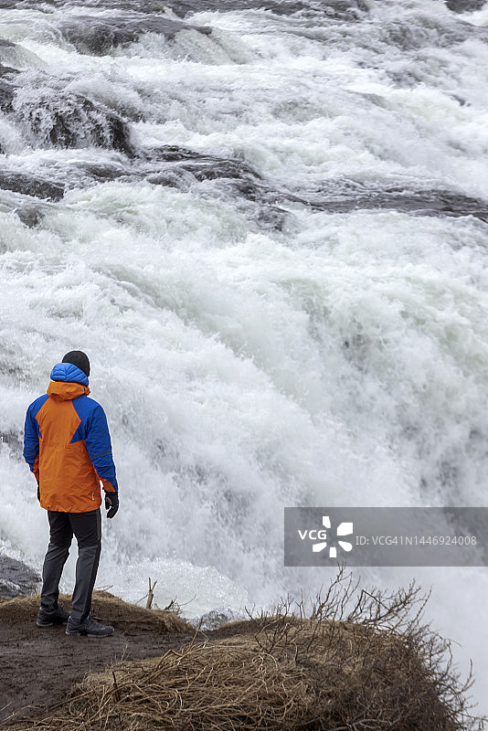 穿着冬装看着Faxi瀑布的男人图片素材