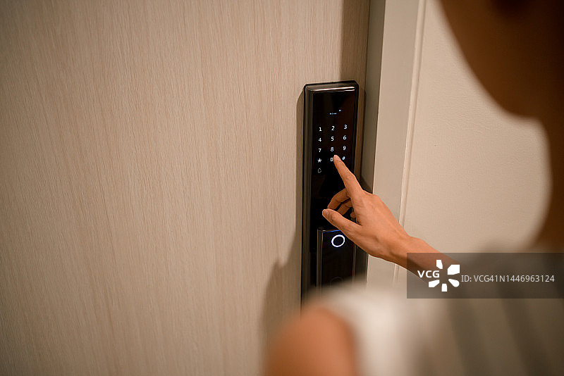 女人在家中电子门禁上输入密码解锁房门图片素材