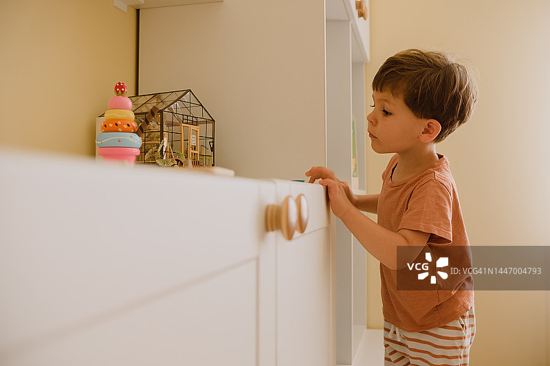 家中儿童房里选择玩具的三岁男孩侧面肖像图片素材